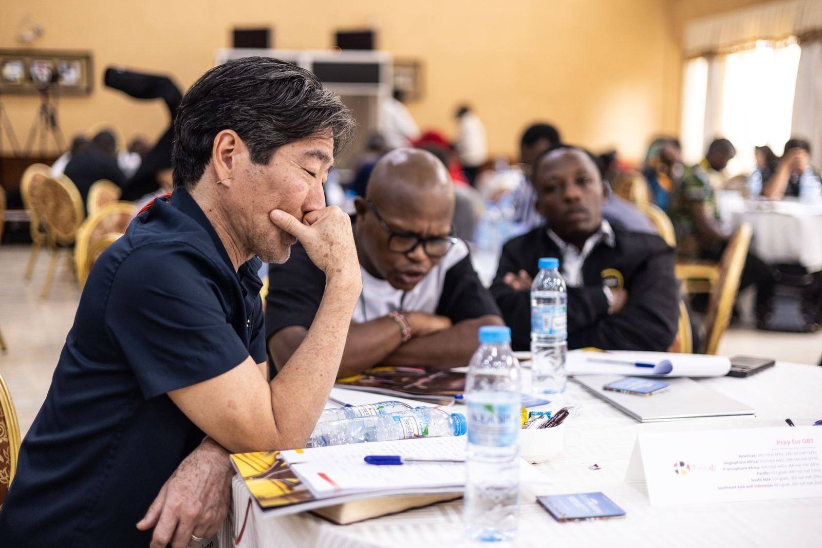 Translators and mentors working together around a table in Entebbe